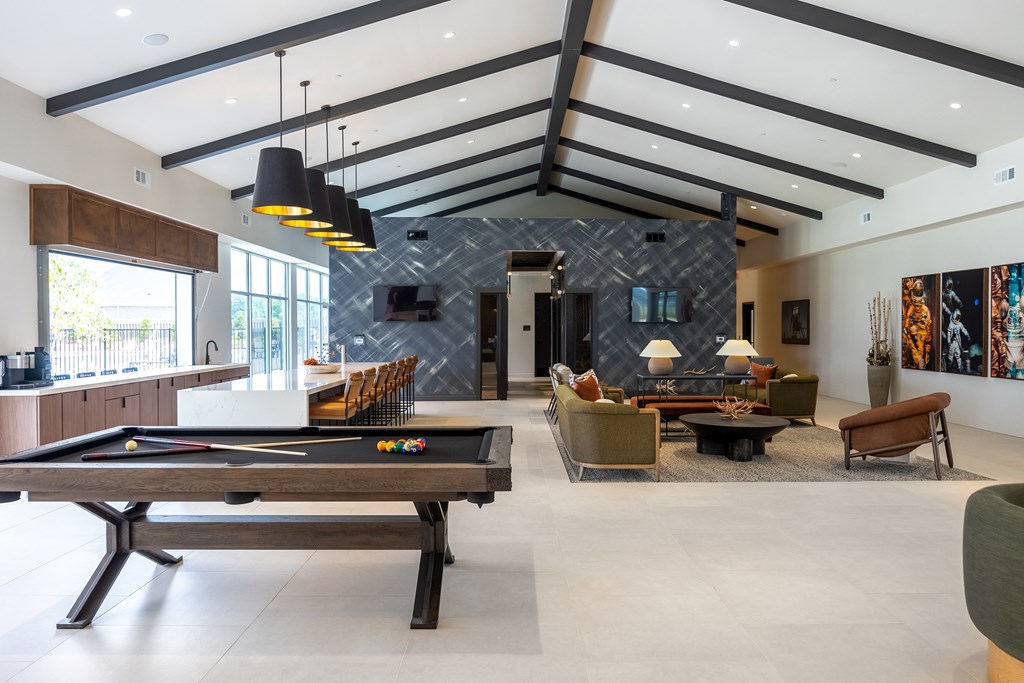 A billiard table is in the middle of a spacious room with a stone wall and a fireplace.