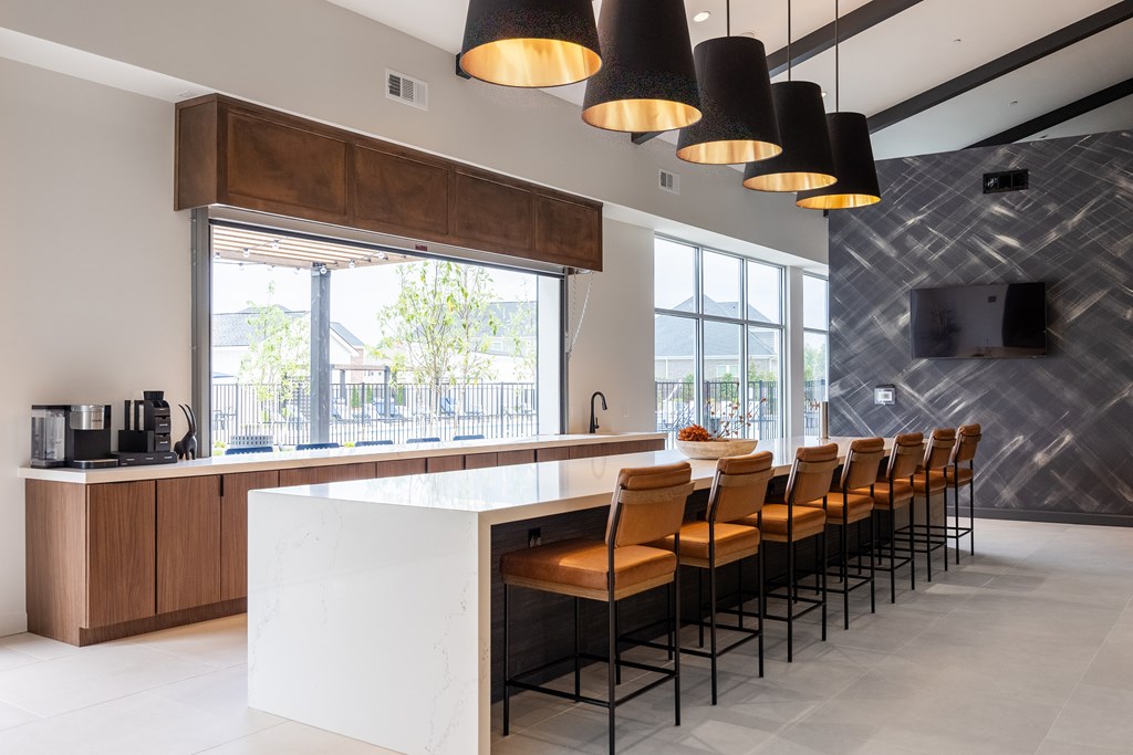 A modern kitchen with a white counter and brown chairs.