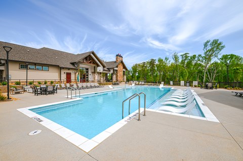 A large outdoor swimming pool with a slide and a building in the background.
