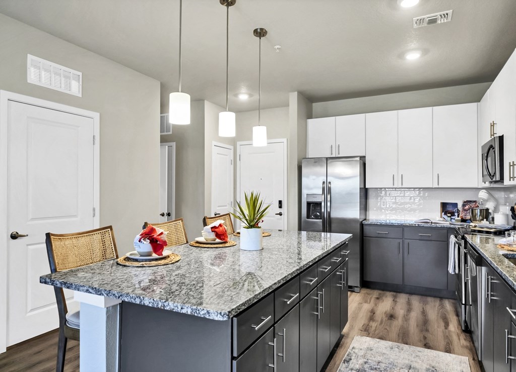 a kitchen with a large island with granite countertops and stainless steel appliances