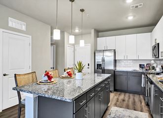 a kitchen with a large island with granite countertops and stainless steel appliances