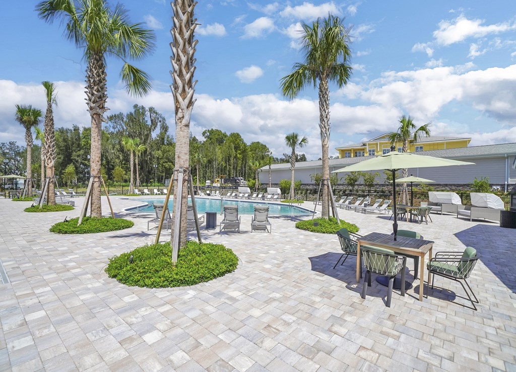 a patio with a table and chairs and a pool in the background