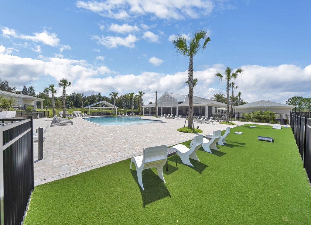 a swimming pool with chaise lounge chairs and palm trees in the background
