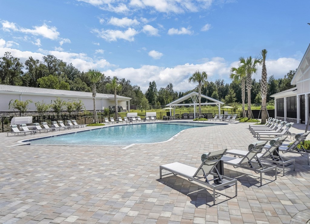 a swimming pool with chaise lounge chairs and palm trees in the background