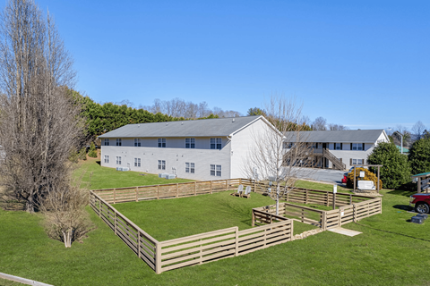 A white house with a grey roof and a wooden fence in front of it.