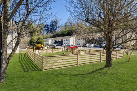 A white house with a red car parked in front.