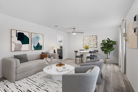 A living room with a grey couch, a coffee table, and a potted plant.