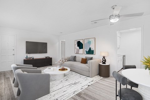 A modern living room with a grey sofa, a white coffee table, and a TV on the wall.
