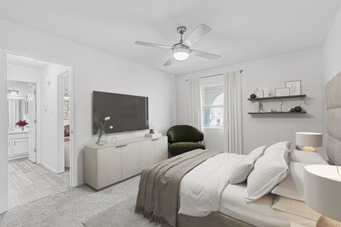 A bedroom with a bed, a television, and a ceiling fan.