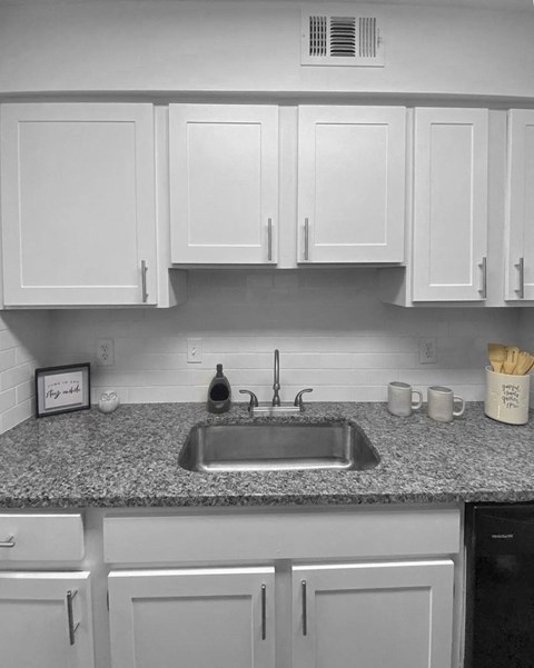 A kitchen with a granite countertop and white cabinets.