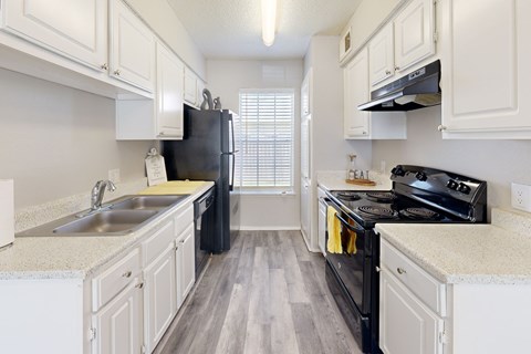 A kitchen with black appliances and white cabinets.
