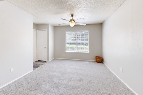 A room with a ceiling fan and a window with blinds.