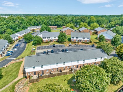 an aerial view of a building with a yard and a parking lot