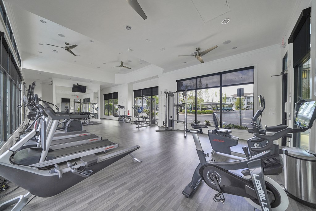 a gym with treadmills and other exercise equipment in a large room with windows