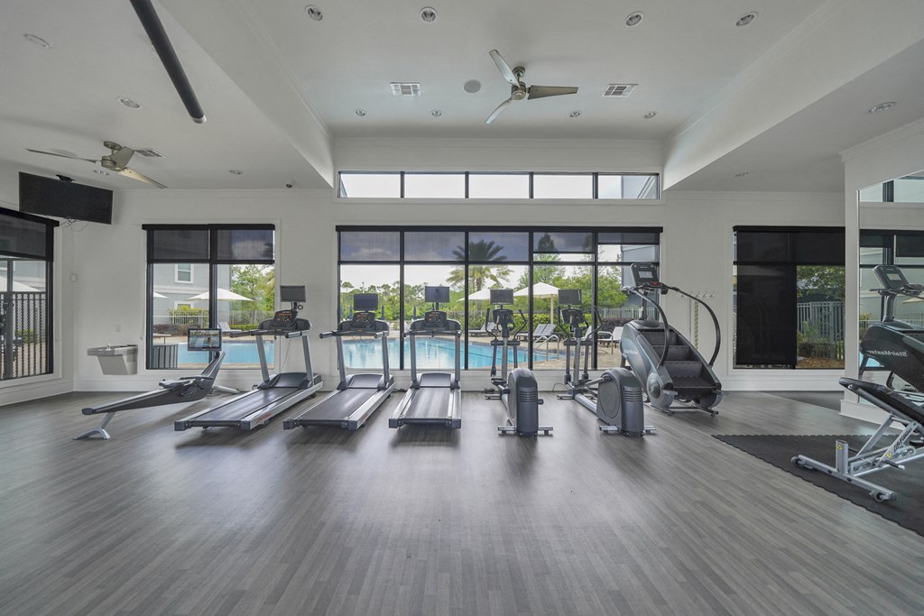 a gym with cardio equipment and a swimming pool