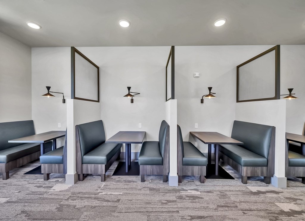 a common area with tables and chairs and three framed pictures on the wall