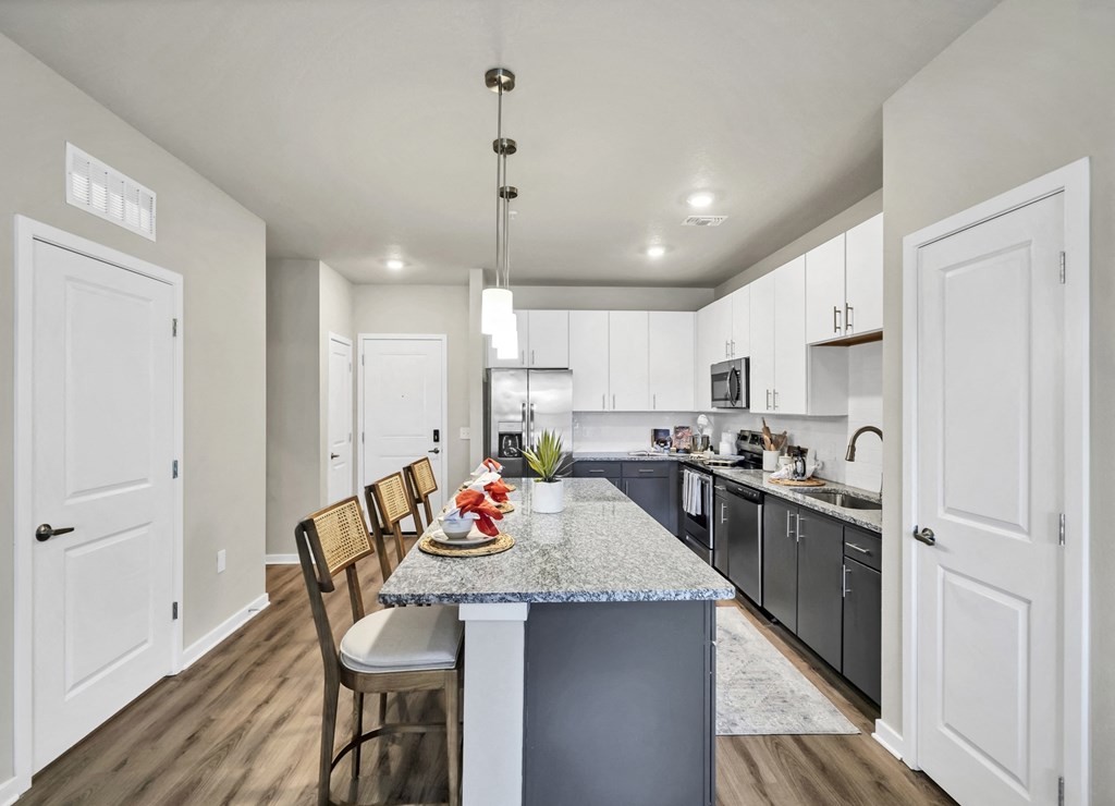 a kitchen with white cabinets and a large island with a granite countertop