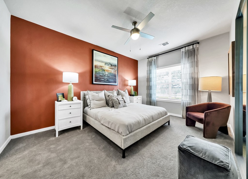 a bedroom with a bed and a chair in front of a window