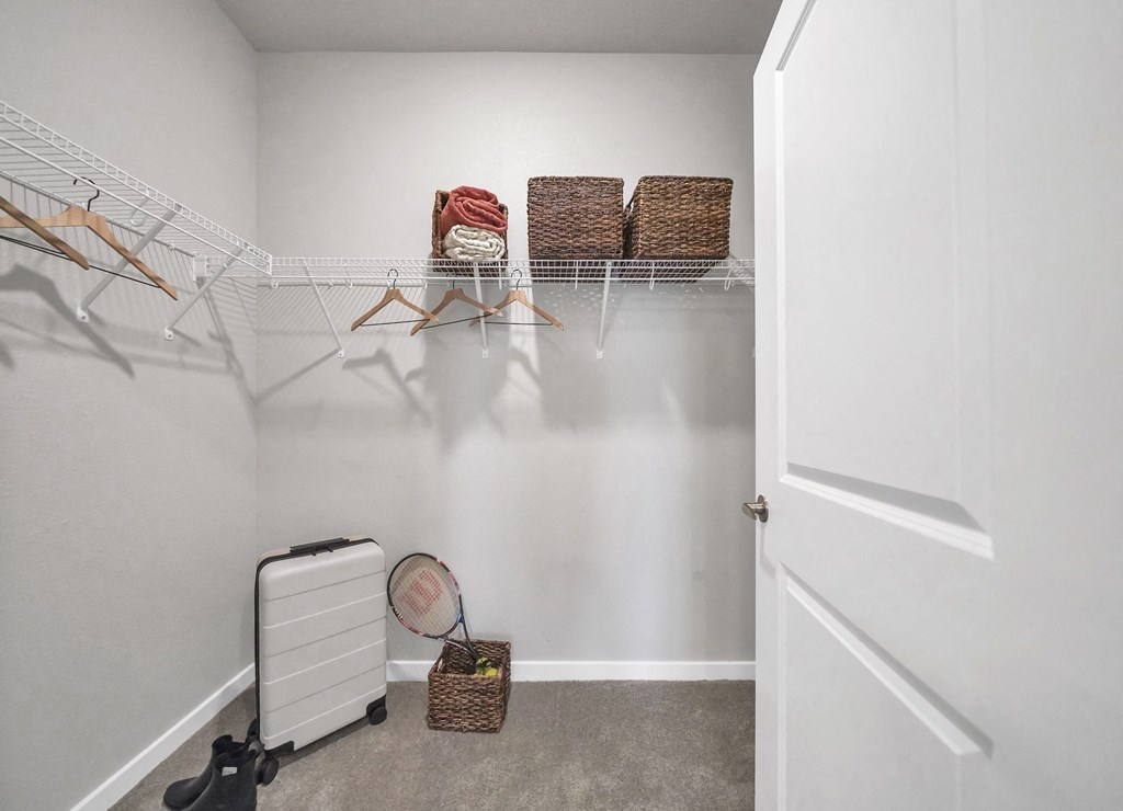 a walk in closet with a clothes rack and a tennis racquet on the floor