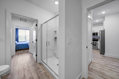 a bathroom with a glass shower and a bedroom with a bed