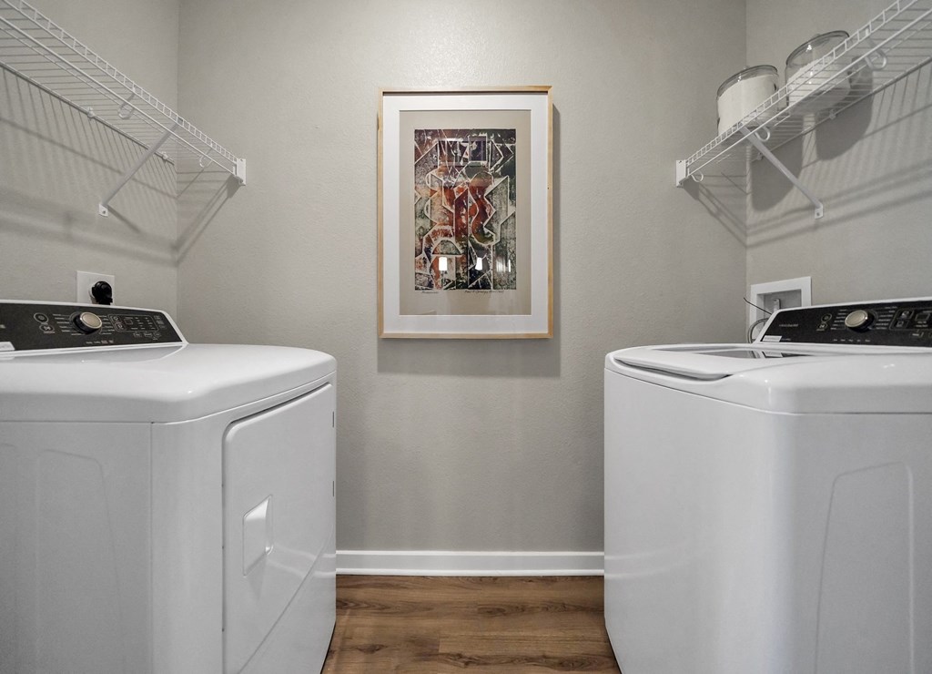 a washer and dryer in a laundry room with a painting on the wall