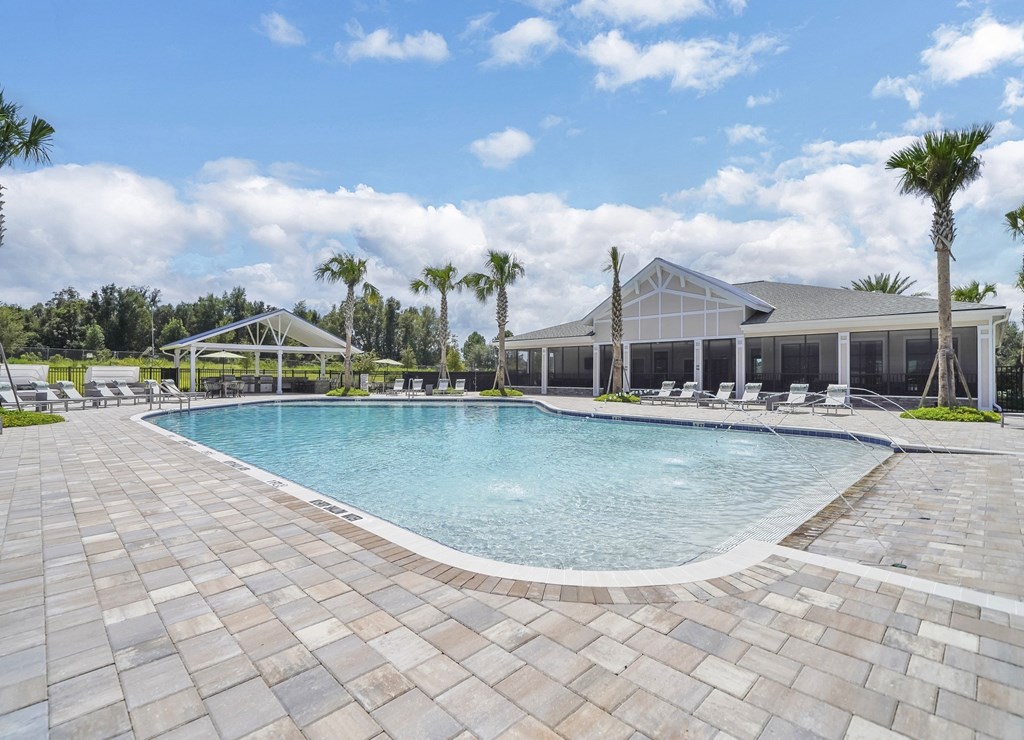 a large swimming pool with lounge chairs and a building in the background