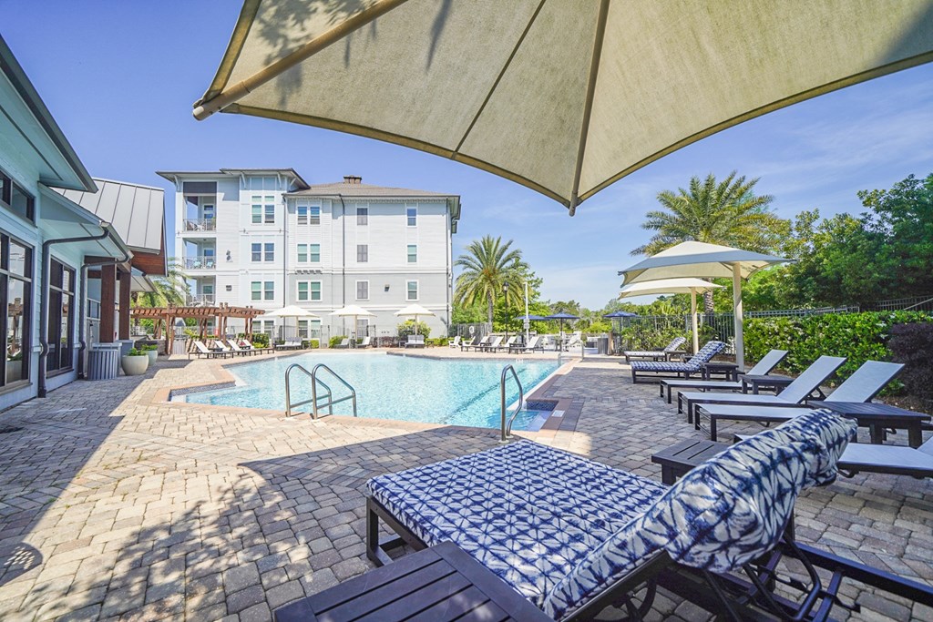 a swimming pool with lounge chairs and umbrellas