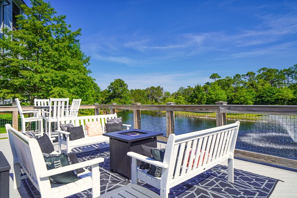 a deck with white benches and a fire pit overlooking a body of water