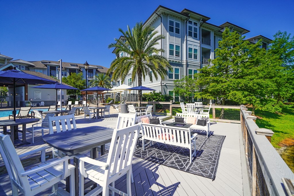 an outdoor patio with tables and chairs and a swimming pool