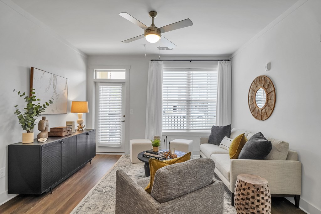 a living room with a ceiling fan and two windows at The Indigo Apartments, Canton, GA