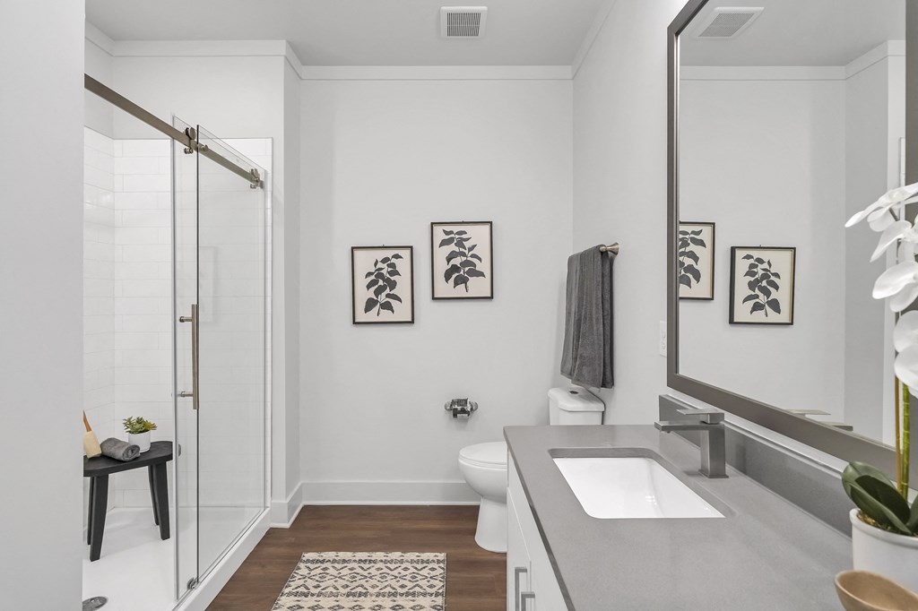 a bathroom with white walls and gray countertops at The Indigo Apartments, Canton, 30114