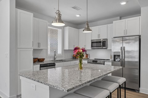 a kitchen with a large island with a vase of flowers on it