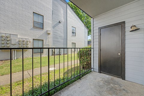 A black metal fence separates a white house from a grey building.