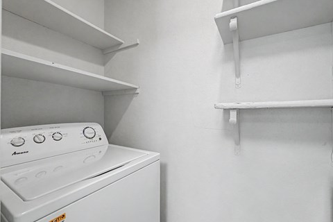 A white dishwasher is sitting in a kitchen next to a wall.