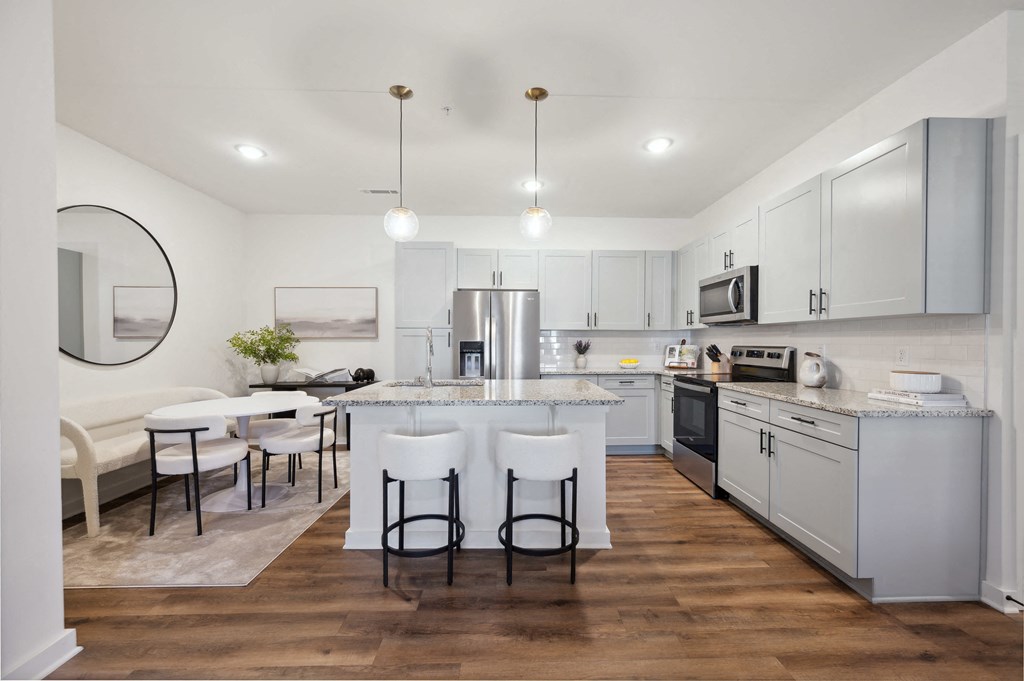 a kitchen with white cabinets and a large island with white chairs