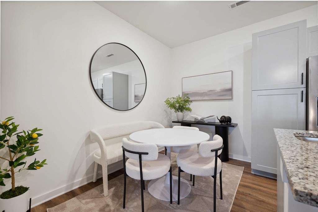 a dining room with a white table and chairs and a round mirror