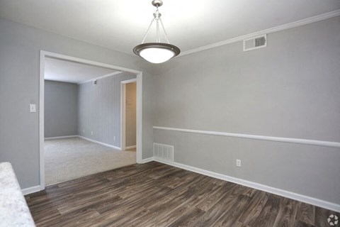 an empty living room with a wood floor and a ceiling light