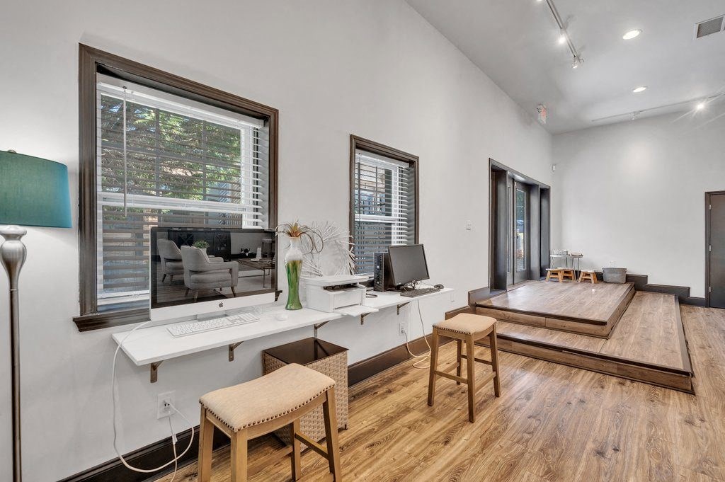 a living room with a desk with a computer and a window