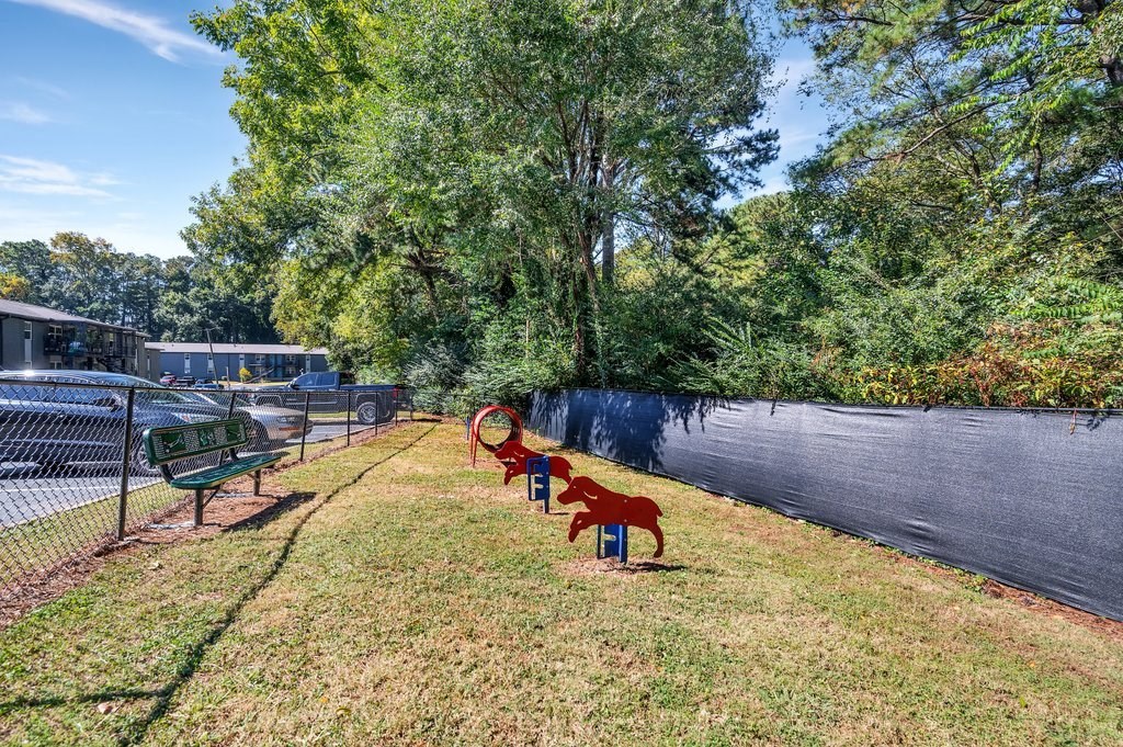 a yard with benches and a chain link fence and trees