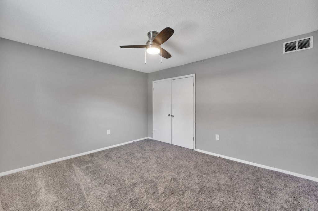 the living room is empty and has a ceiling fan