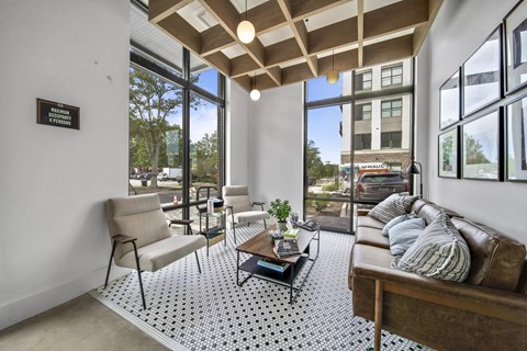 a living room with a couch and chairs and large windows
