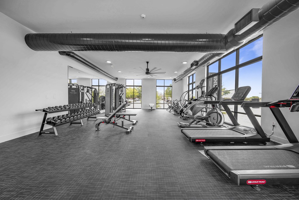the gym has treadmills and other exercise equipment and windows