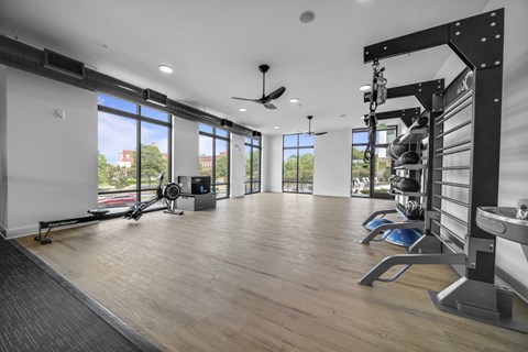 a home gym with windows and a wood floor