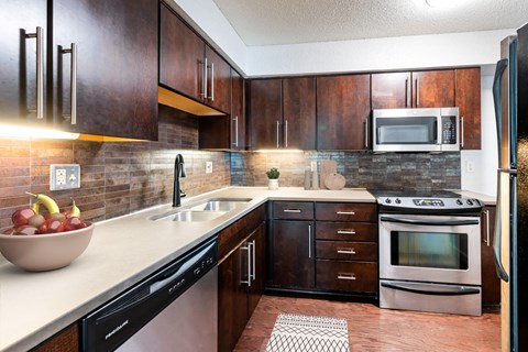 A kitchen with dark wood cabinets and a black fridge.