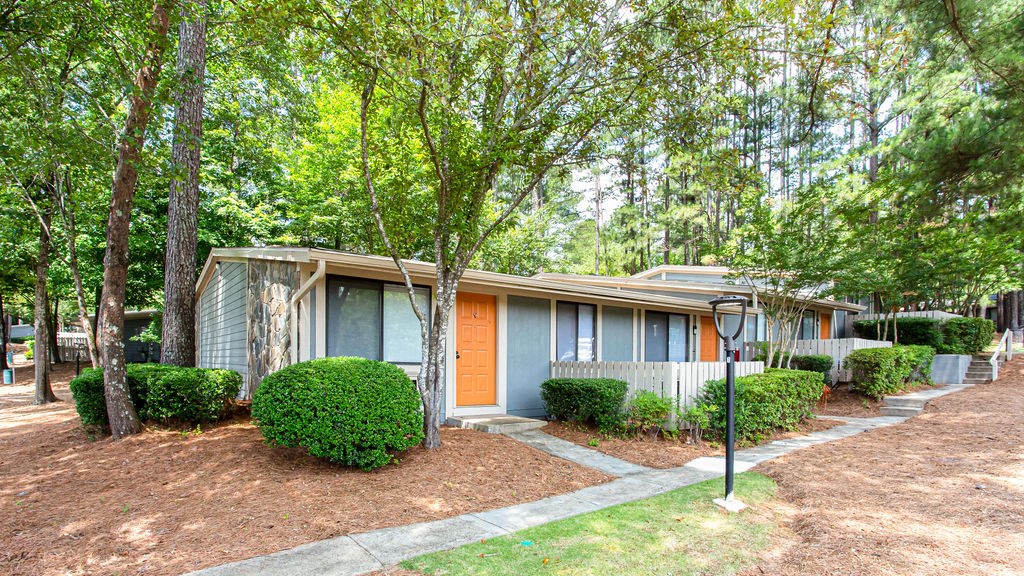 a small blue house with an orange door in a wooded area