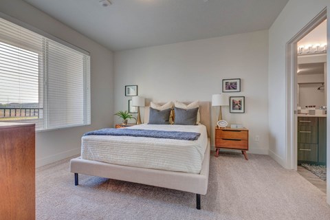 A bedroom with a large bed and a nightstand with a lamp.