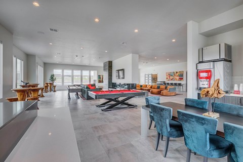 A modern dining room with a pool table and blue chairs.