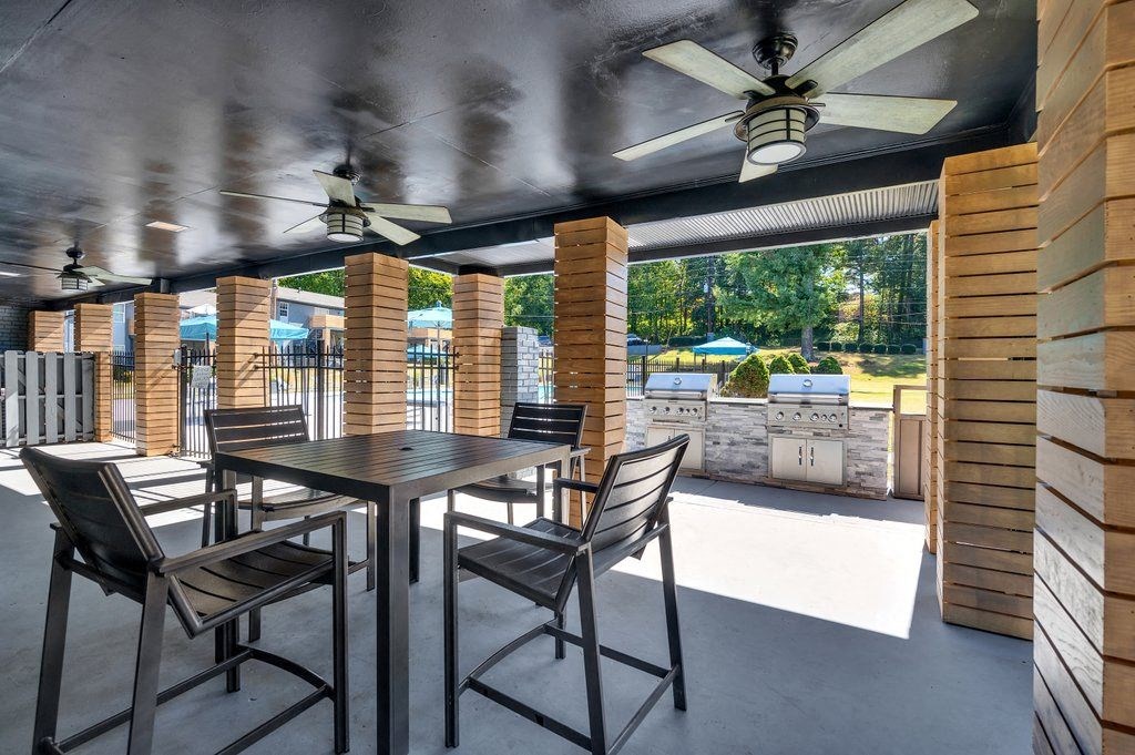 a covered patio with tables and chairs and a grill