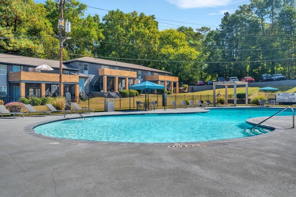 a resort style pool with chairs around it and buildings in the background