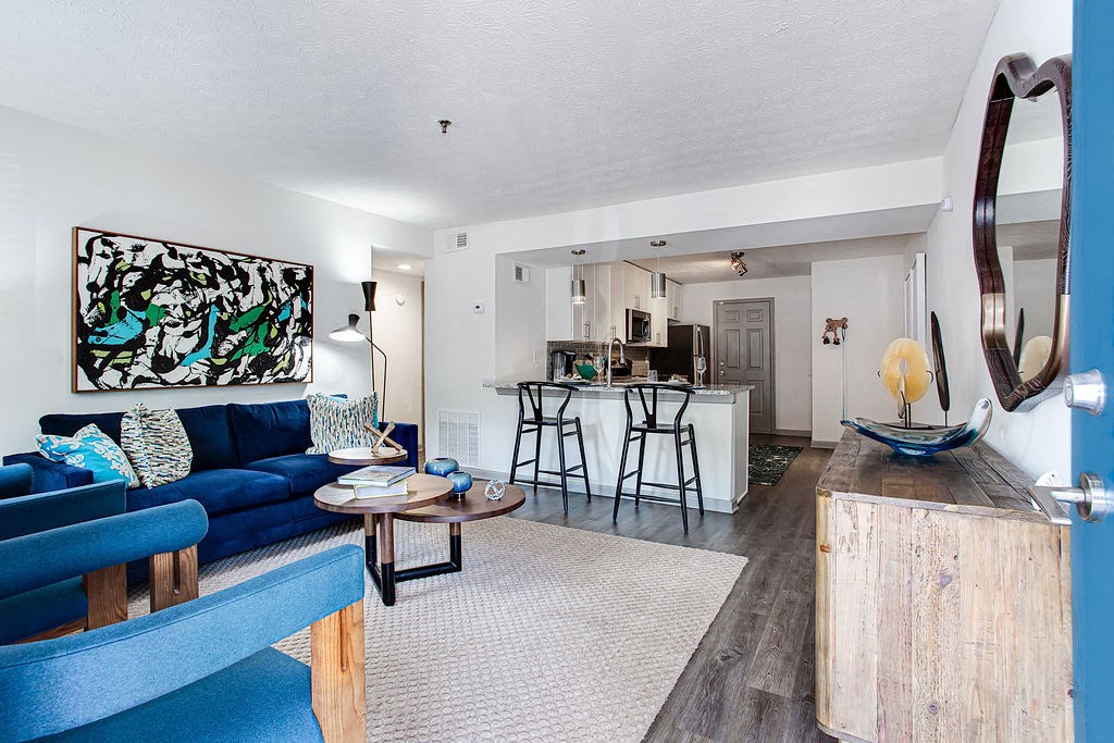 a living room with a blue couch and a kitchen in the background